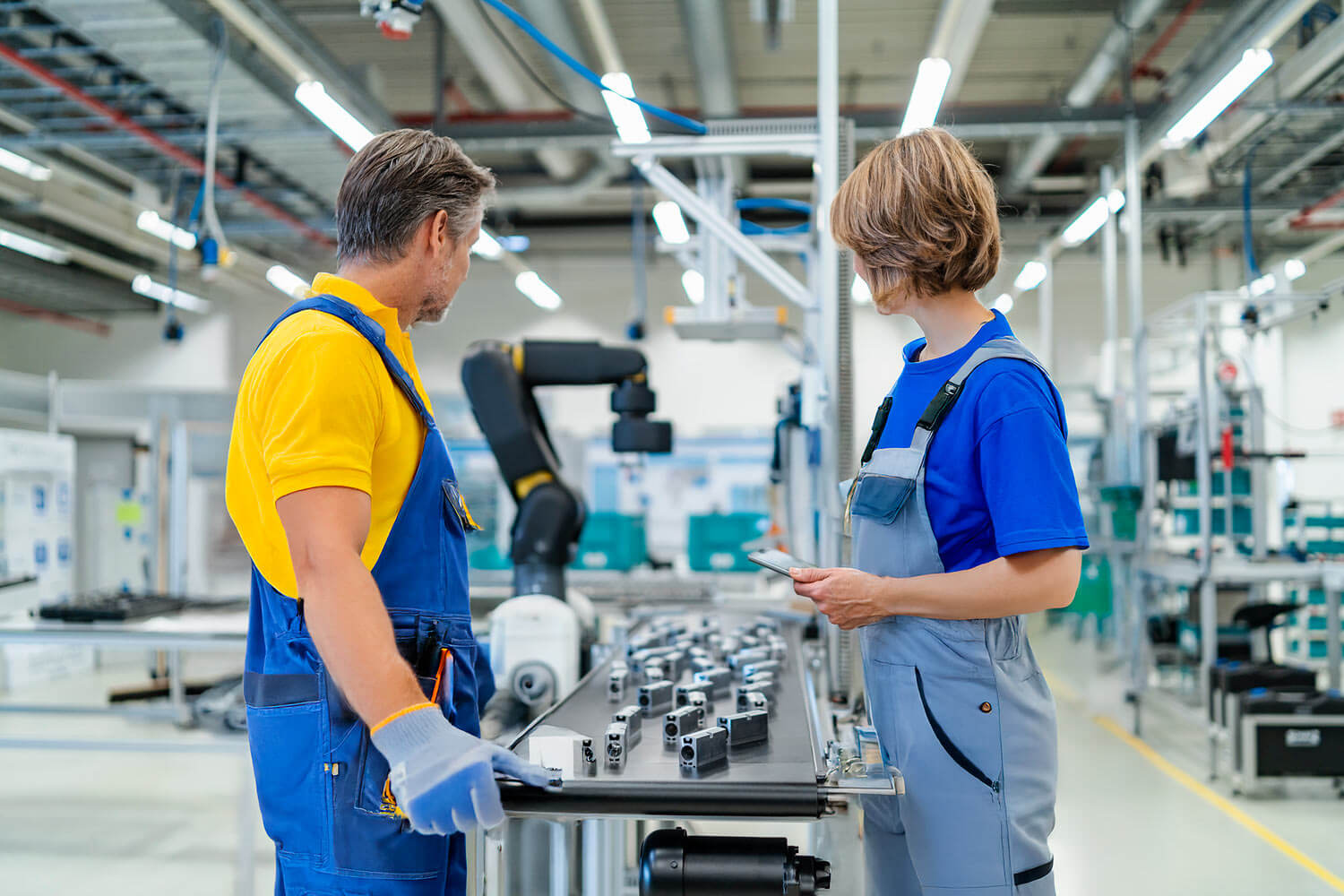 Mann und Frau arbeiten in der Produktion mit SAP Business One auf einem Smartphone