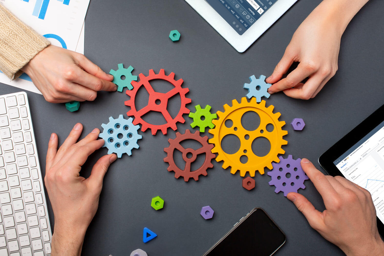 Vier Hände fügen Zahnräder zusammen, die für die nahtlosen Schnittstellen in SAP Business One stehen