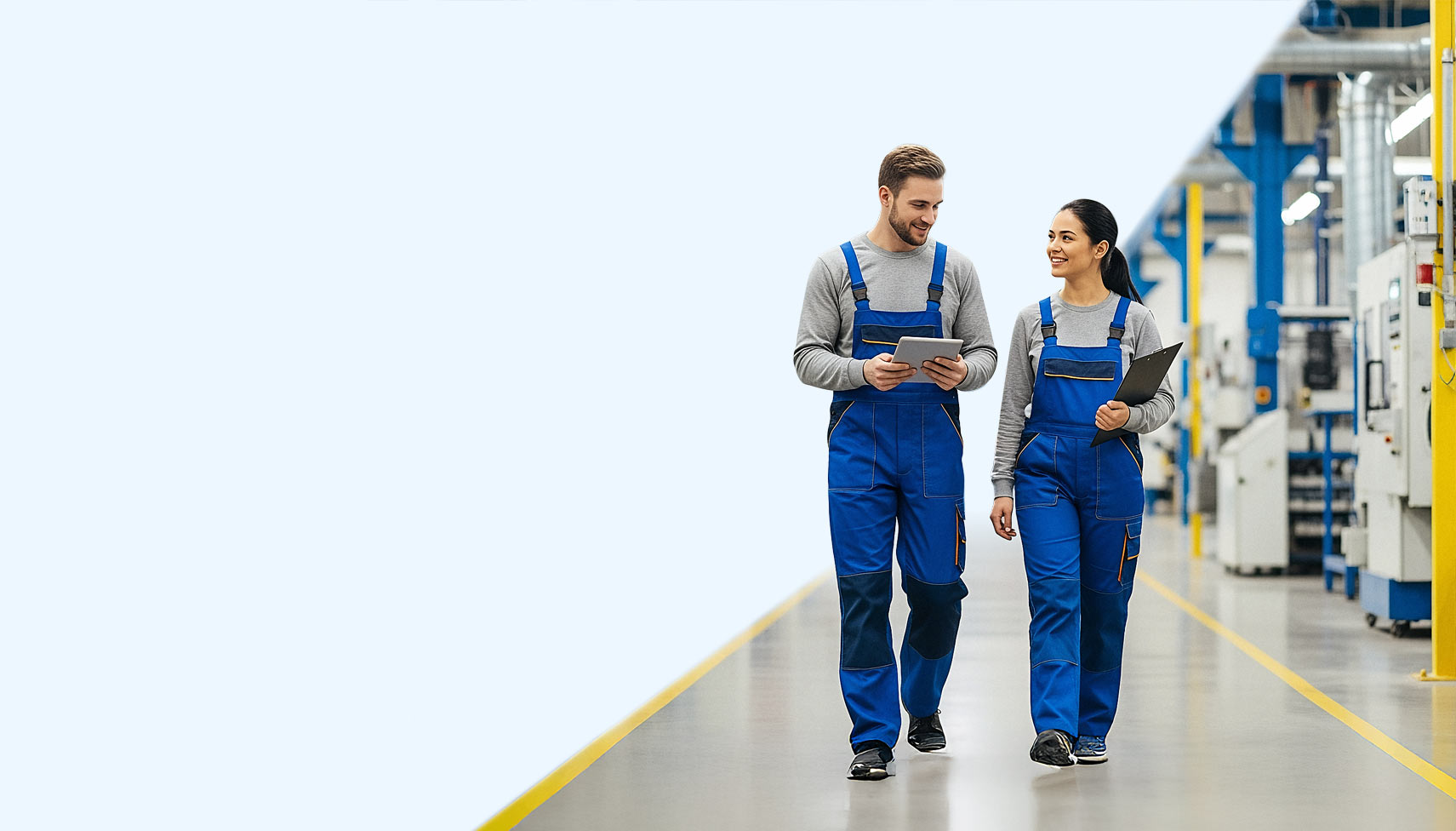 Mann und Frau gehen mit SAP Business One auf Tablets durch eine Halle eines produzierenden Unternehmens